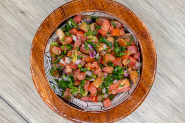 Overhead view of freshly made pico de gallo salsa served in a wooden bowl for a Mexican cuisine presentation