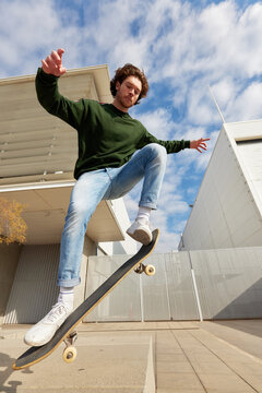 Energetic guy doing flip trick while riding skateboard