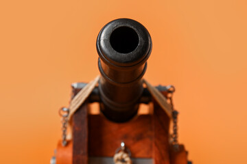 Toy model of cannon on orange background, closeup