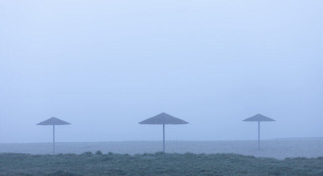 three beach umbrellas in the fog
