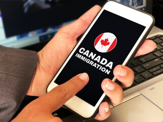 Applying for Canada Immigration concept background with man touching on the screen. Person touching the mobile screen and applying for Immigration