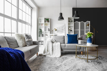 Interior of bright living room with cozy sofas and coffee table near big window