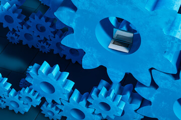 Laptop computer next to cogwheel gears