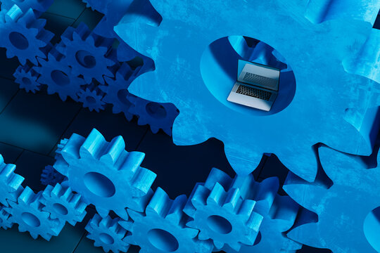 Laptop computer next to cogwheel gears