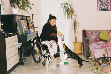 A girl in a wheelchair at home playing with her dog