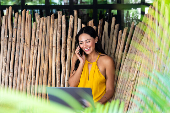 Smiling woman talking on smartphone working outdoors