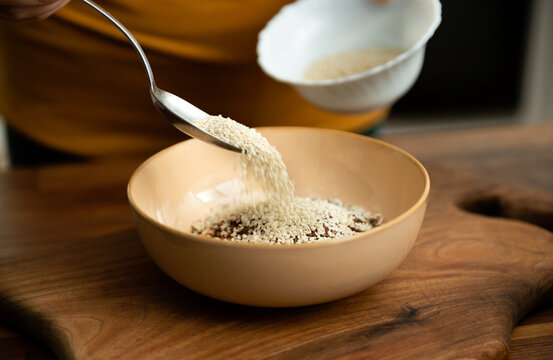 Making muesli oats breakfast with nut milk. Adding sesame seeds.