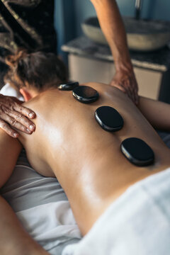 Masseur applying hot stones on a patient
