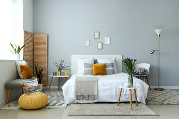 Interior of stylish bedroom with blooming iris flowers on bedside table