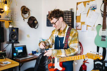 Handy man with cord of electric guitar