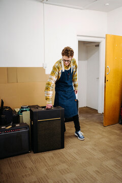 Repairman carrying retro amplifier in repair shop