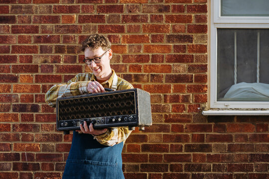 Happy worker repairing vintage amplifier against wall