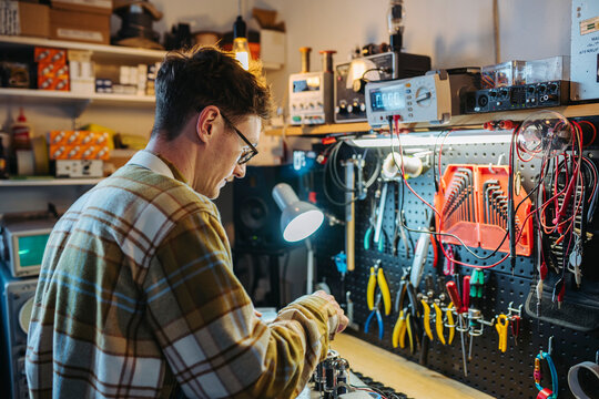 Repairman fixing details of guitar amp at workbench