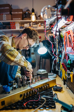 Attentive male master repairing guitar amplifier
