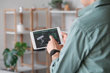 Young man using smart home security system control panel, closeup