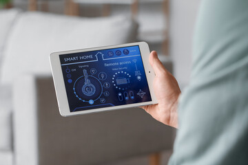 Young man using smart home security system control panel, closeup