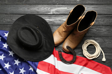 Composition with different cowboy accessories and flag of USA on black wooden background