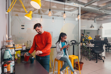 Young man preparing a coffee in cozy office kitchen