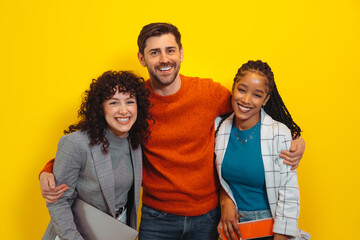 Portrait of happy diverse colleagues posing over yellow wall