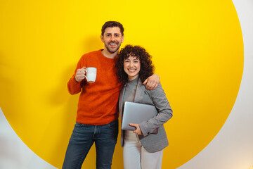 Portrait of happy diverse colleagues posing over yellow wall