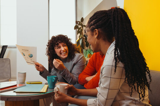 Cheerful multiethnic friends talking while sitting at table in c - Powered by Adobe