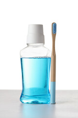 Bamboo toothbrush and mouthwash on table against white background