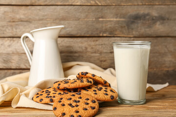 Tasty cookies with chocolate chips and glass of milk on wooden background