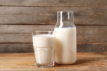 Bottle and glass of fresh milk on wooden background