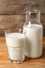 Bottle and glass of fresh milk on wooden background