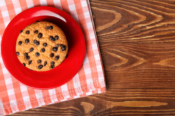 Plate of tasty cookies with chocolate chips on wooden background