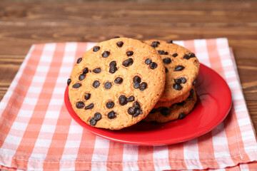 Plate of tasty cookies with chocolate chips on wooden background