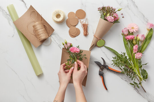 Female florist putting spring flowers in paper.