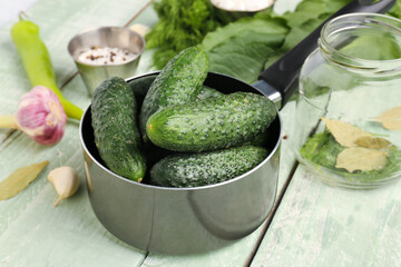 Saucepan with fresh cucumbers for preservation on light wooden background