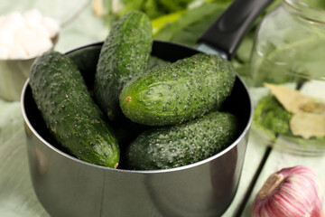 Saucepan with fresh cucumbers for preservation on table, closeup