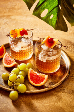 Two Whiskey Cocktails on a Brass Tray with grapes
