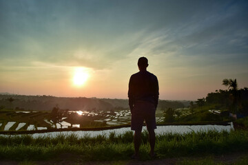 silhouette of a a man alone enjoy the sunrise in a field