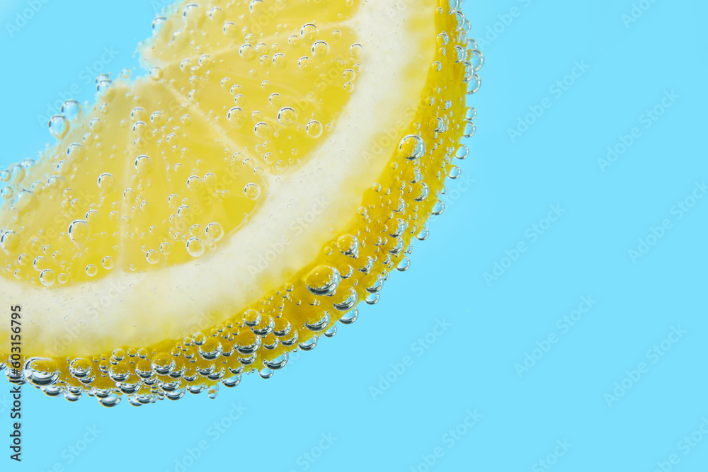 Wall mural Lemon slice in water with bubbles on blue background