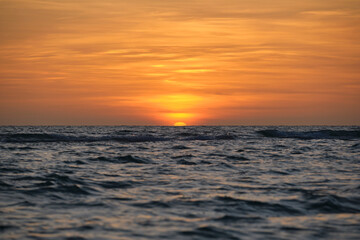 Fototapeta na wymiar Ocean sunset. Big white sun on dramatic bright sky background, soft evening horizont over sea dark water