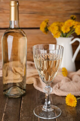 Bottle and glass of dandelion wine on wooden table