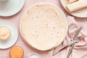 Plate with fresh lavash and sauces on pink tile background