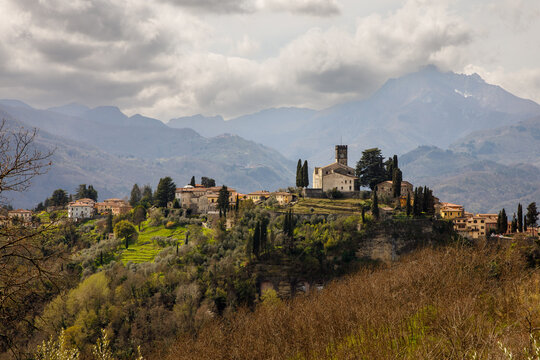 Small village under Alps mountains. Dramatic clouds over Alpi Apuane mountains and Barga town in Italy, Europe.