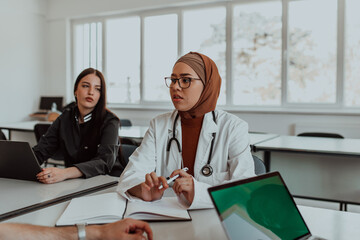 In a modern meeting room, a Muslim female doctor wearing a hijab engages in a discussion with her...