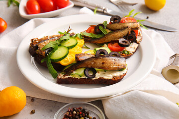 Plate of tasty sandwiches with canned smoked sprats on table