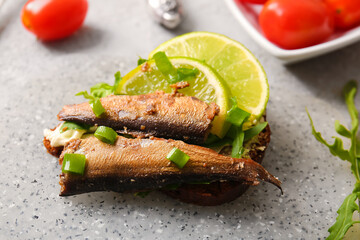 Tasty sandwich with canned smoked sprats on table