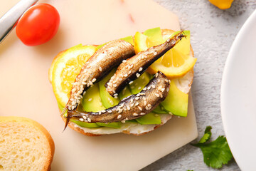 Board of tasty sandwiches with canned smoked sprats on table