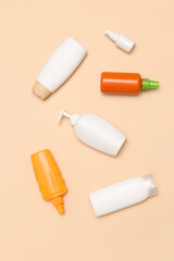 Different bottles of sunscreen cream on pale orange background