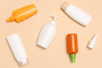 Different bottles of sunscreen cream on pale orange background