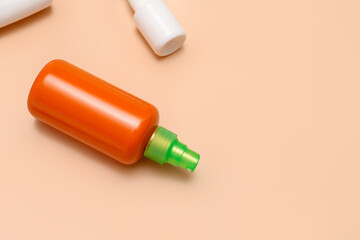 Different bottles of sunscreen cream on pale orange background