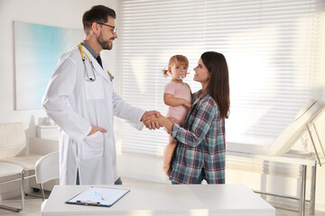 Obraz premium Mother and her cute baby having appointment with pediatrician in clinic. Doctor examining little girl