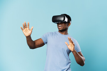 Smiling african man playing video game in VR glasses isolated on blue background. Excited male gamer © Maria Vitkovska